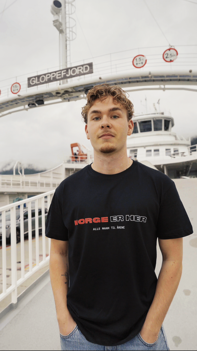 Man wearing the Norge er Her tee on the ferry deck