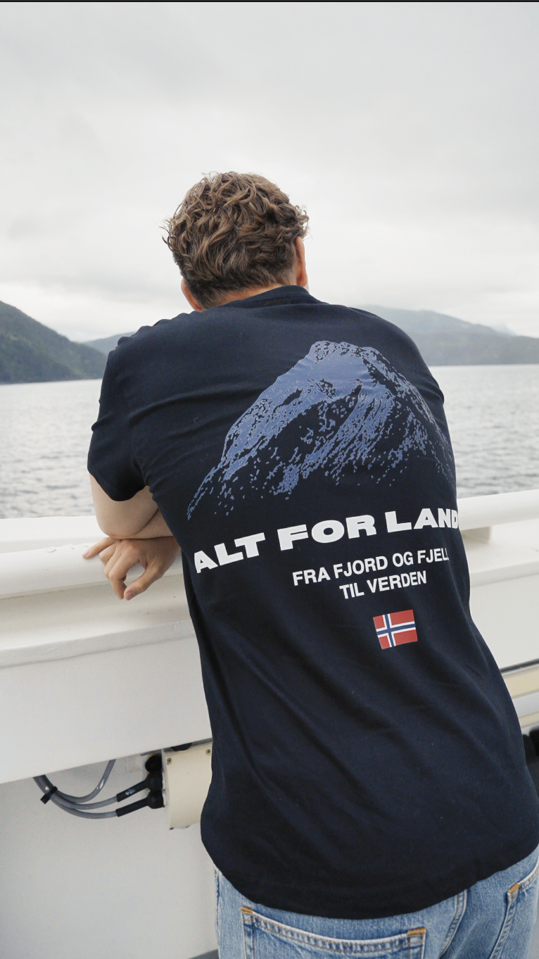 Man wearing the Alt for Landet tee looking out over the fjord